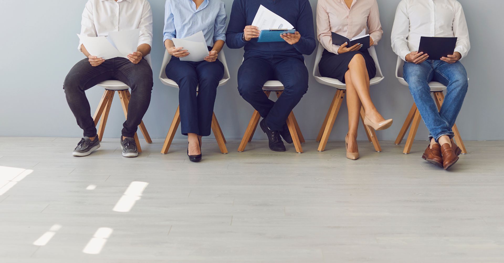 five people sat on chairs with papers
